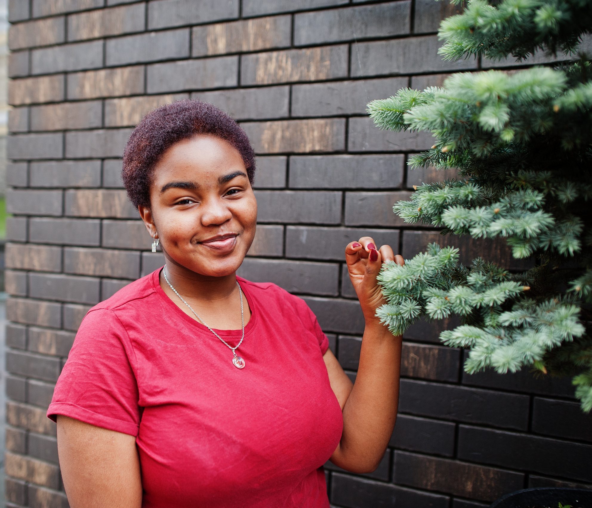 African woman wear red t-shirt posing outdoor.